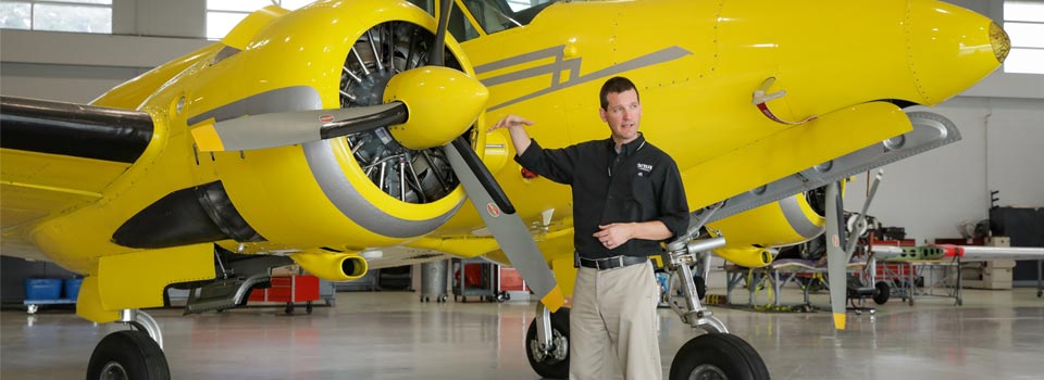 An instructor teaching in front of a yellow airplane