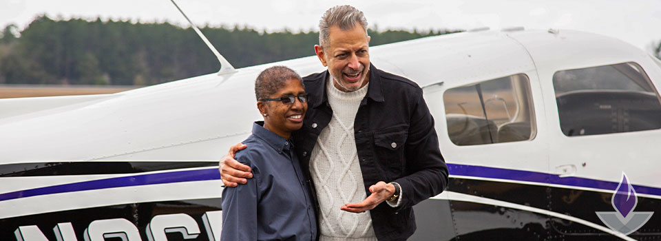 Jeff Goldblum and an instructor, Lisa, in front of a small airplane